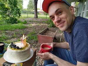 A man in a red hat and blue shirt sitting at a table outside