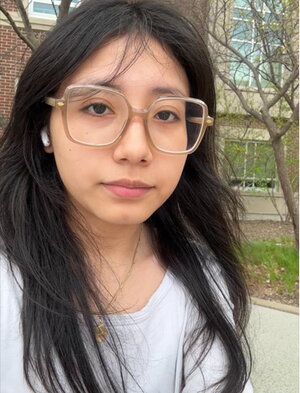 A woman wearing glasses outside of a building