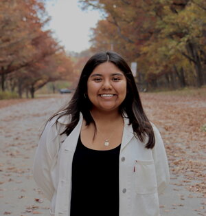 A smiling woman standing in the road with leaves on it
