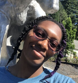 A smiling woman in glasses and a blue shirt outside