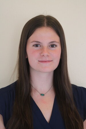 A woman wearing a blue shirt in front of a beige wall