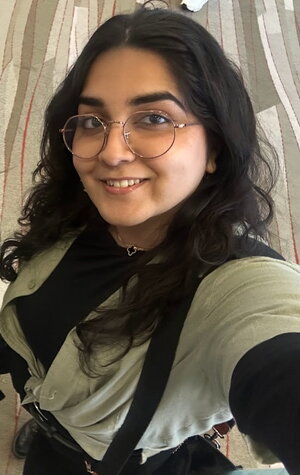 A smiling woman in round glasses and a green shirt