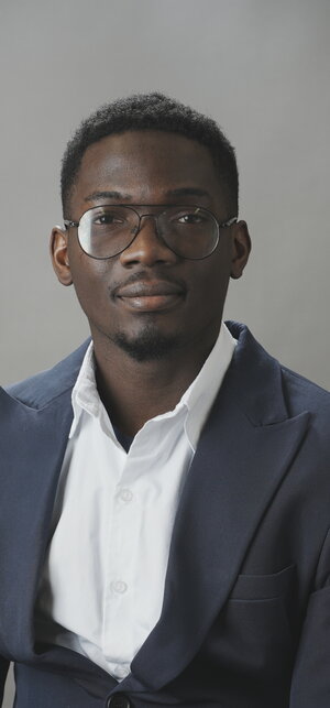 A man in glasses, a blue blazer, and a white button up shirt