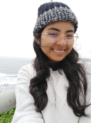 A smiling woman with long hair and wearing a stocking cap outside
