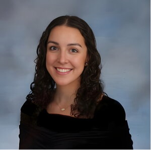 A smiling woman with curly hair and wearing a black shirt 