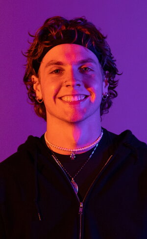 a smiling man in a black hoodie in purple lighting