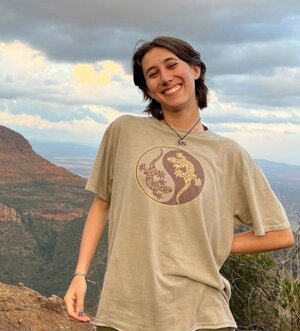 A smiling woman in a tshirt with desert plateaus in the background