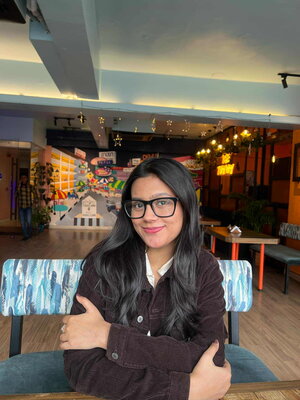 A woman in a brown jacket smiling in a restaurant