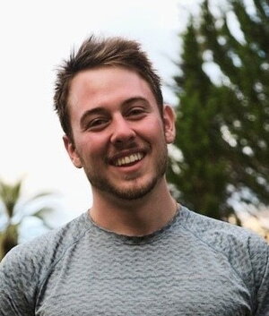 A smiling man in a grey shirt outside