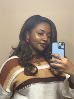 a woman wearing a sweater and taking a selfie with a phone