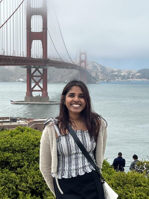 A woman smiling in a striped shirt in front of the golden gate bridge