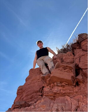 A man standing on some rocks looking down at the camera