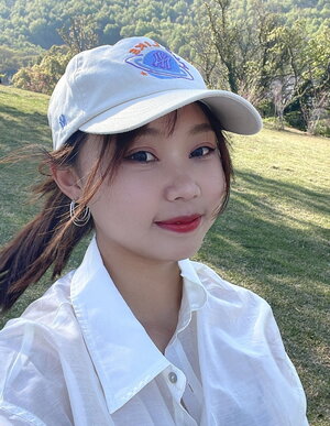 A woman in a white hat and white button up shirt outside