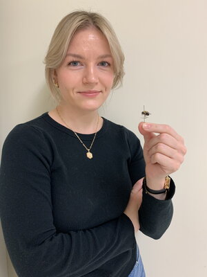 A woman in a black holding a pinned insect