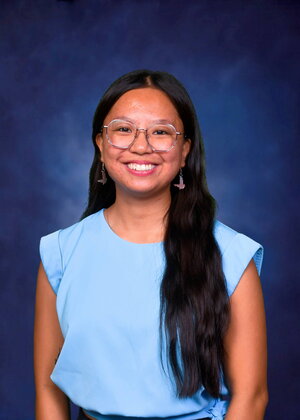 A smiling woman in a blue shirt with long black hair