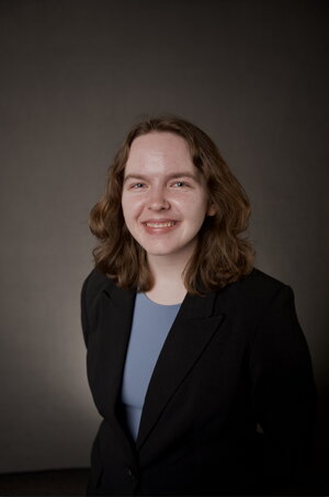 A smiling woman in a black suit jacket and blue shirt