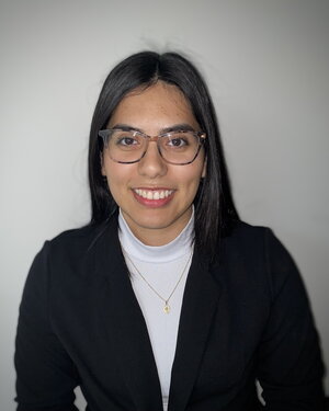 A smiling woman in glasses wearing a black sweater and white shirt