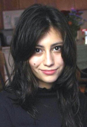 A smiling woman with long black hair in a black sweater