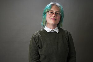 A person with turquoise hair in a sweater and button up shirt underneath