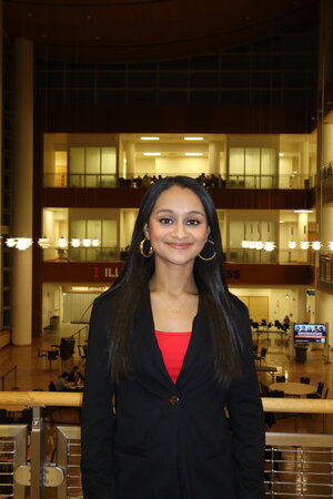 A smiling woman in a suit smiling in front of a balcony