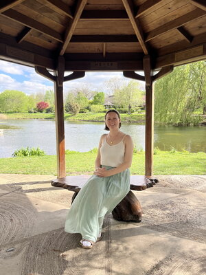 A woman sitting in a gazebo in a white top and green dress