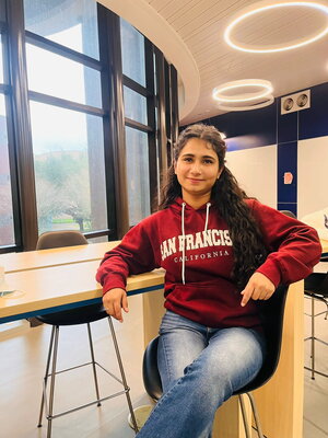 A woman in a red hoodie sitting inside a building