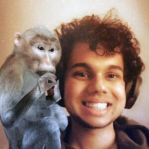 A smiling man with wearing headphones with a monkey next to him