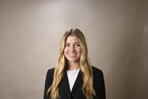 A smiling blonde woman in a black jacket