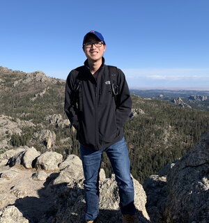 A man in a black jacket and hat standing on a mountainside