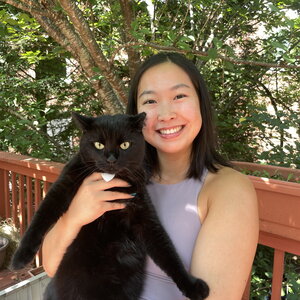 A smiling woman sitting outside holding a black cat
