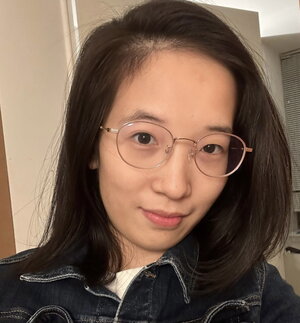 A smiling woman with long hair and round glasses