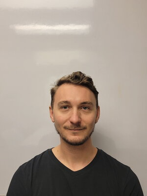 A smiling man in a black v-neck