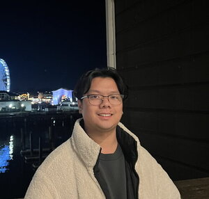 A man smiling in a coat outside in the dark