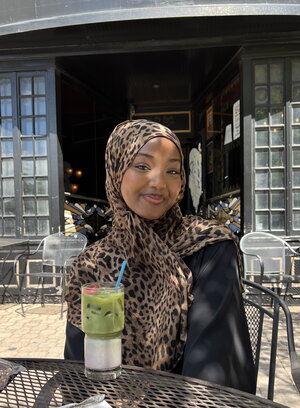 girl sitting with drink in front of building 