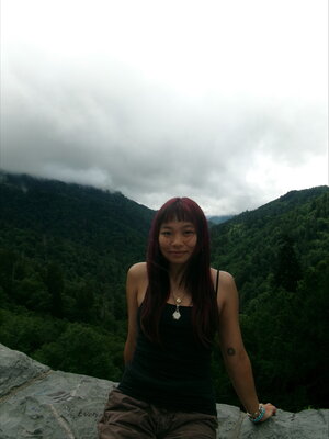 girl sitting on a rock in front of a mountain landscape