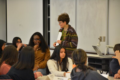 A student talking into a microphone with other students around her