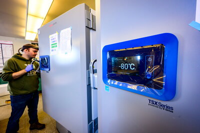 A man standing at a lab fridge