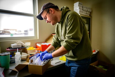 A man in a hat wearing gloves going through a box