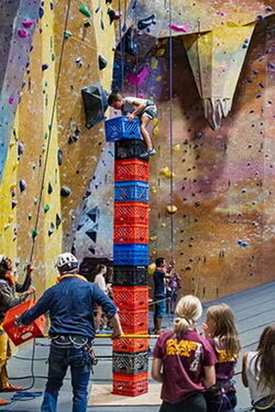 Stacked crates with a kid climbing them while others watch