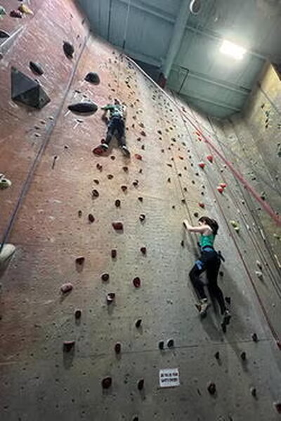 Two people climbing a rock wall