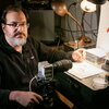 man sitting at desk with camera and pencil