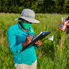 person writing on a clipboard in a field