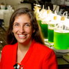 smiling woman in a lab with green fluid