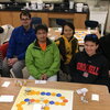 six people sitting in front of a board game