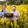 Two men standing in a field holding bees