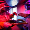 A man and woman in bee suits holding parts of a bee hive