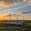 A photo of a field at sunset with a rain canopy over a part of it
