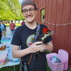 A photo of a man in a t-shirt and headband holding a bird at an outdoor event