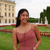 A photo of a woman in a pink dress with a grassy garden and a building behind her
