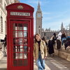 a woman standing next to a red telephone box